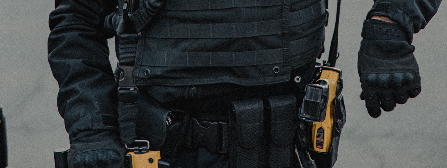 A police officer in tactical gear with an assortment of tools on their belt.